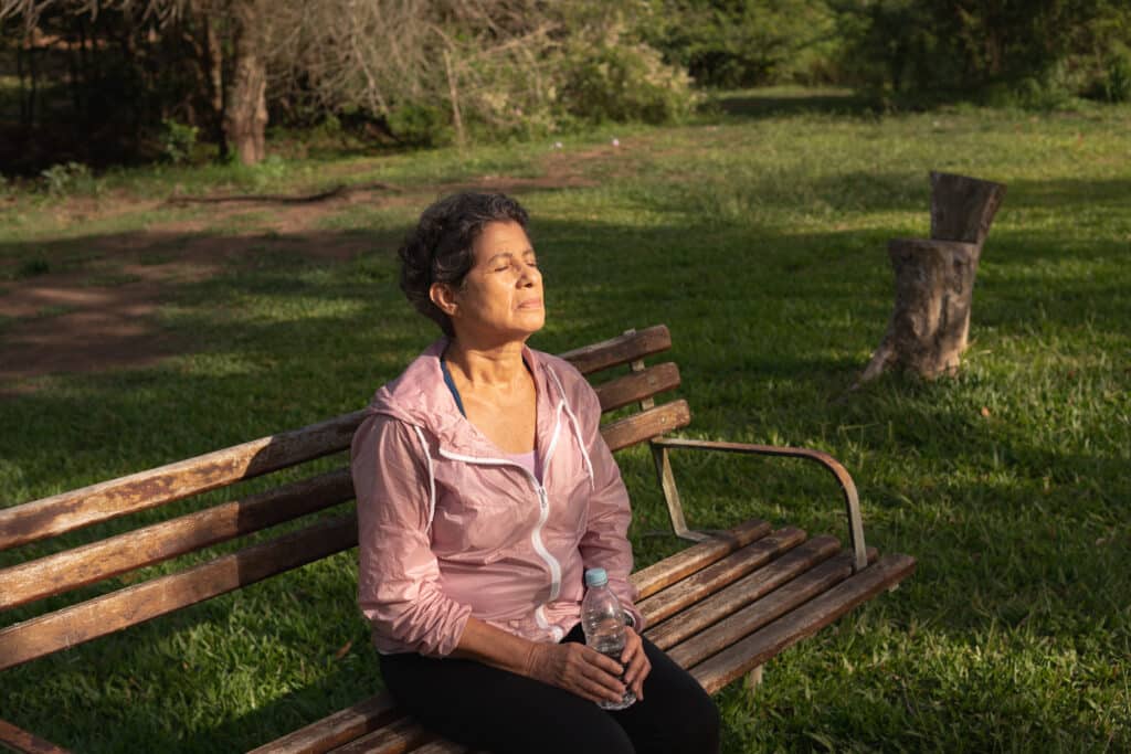 older woman sitting on bench in sun